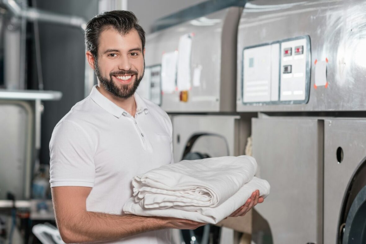 happy-dry-cleaning-worker-holding-stack-of-clean-clothes